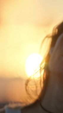 Gün batımında kablosuz kulaklıklarla müzik dinleyen genç bir kadın.