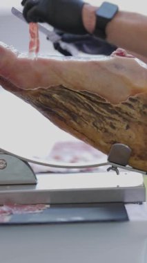 Şef, özel bir tutucuya yerleştirilmiş bir bacağından ince dilim İber jambonu ustalıkla kesiyor.