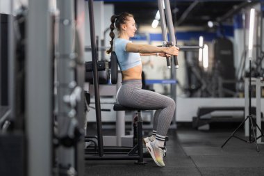 Genç bir kadın spor salonunda çalışırken güç ve kas geliştiriyor.