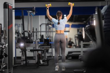 Kadın sporcu, güç ve zindelik için modern spor salonunda üstten baskı yapıyor.