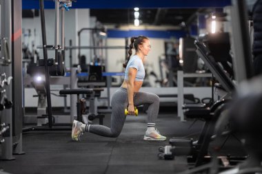 Genç bir kadın ağırlık çalışıyor, modern bir spor salonunda bacak çalıştırıyor.