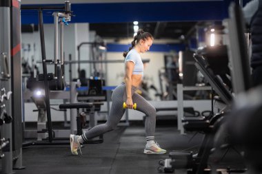 Hafif ağırlıklarla egzersiz yapan, güç toplayan ve fitness geliştiren bir kadın.