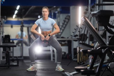 Bir kadın spor salonunda spor yapmak için sumo sumo yapıyor.