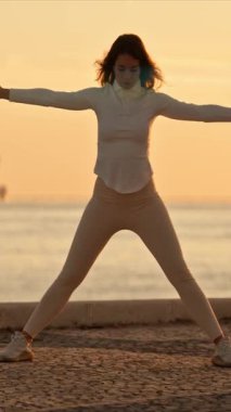 Tagus nehrinin kıyısında şafakta Tai Chi Chuan egzersizleri yapan kadın.