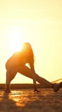 Altın saat boyunca çatıda yoga yapan bir kadın.