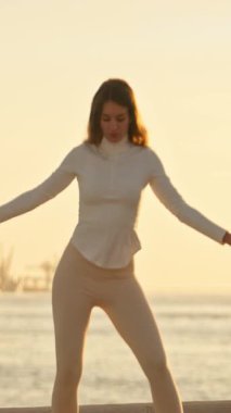 Zarif dansçı günbatımında Lisbons şehir manzarasına karşı zarif hareketler sergiliyor.