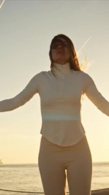 Enerjik kadın gün doğumunda nehrin kenarında atlama ipiyle egzersiz yapmaktan hoşlanıyor.