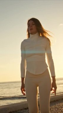 Şafak vakti Tagus nehrinde Tai Chi pratiği yapan zarif bir kadın, arka planda Lizbon şehri.