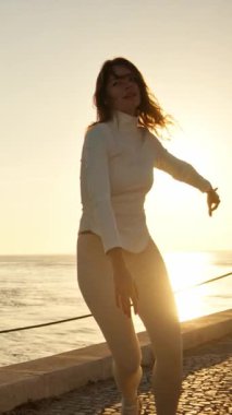 Tai chi chuan egzersizleri yapan bayan sporcu gün doğumunda iskelede