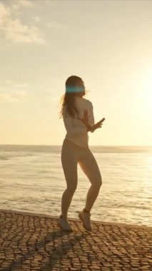 Gün batımında Lizbon 'da nehir kıyısında koşan enerjik genç bir kadın.