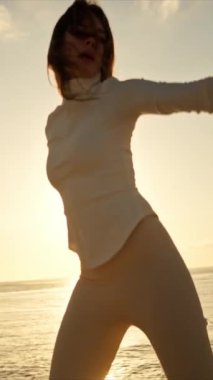 Gün batımında iskelede dans eden kadın, altın saatin tadını çıkarıyor.