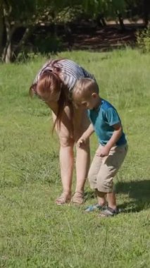 Güneşli bir yaz gününde çimenlerde birlikte yürüyen anne ve çocuğuyla mutlu bir aile.