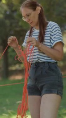 Genç anne ve oğlu yeşil güneşli bir parkta ağaç gövdesi etrafında halat ağ labirenti oluşturuyorlar.