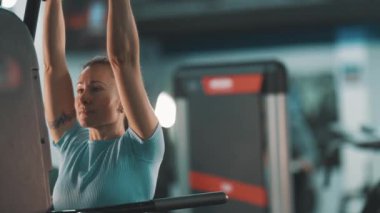 Kaslı kadın bacak kaldırıyor, karın kaslarını ve karnını spor salonunda eğitiyor.