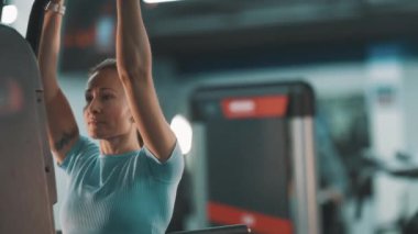 Sırtı güçlü atletik bir kadın spor salonunda barfiks egzersizleri yapıyor.