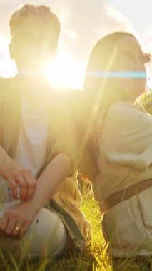 Genç çift altın saat günbatımında çayırda dinleniyor.