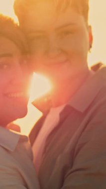 Romantik lezbiyen çift, altın bir günbatımında kumsalda hassas bir anın tadını çıkarıyor.