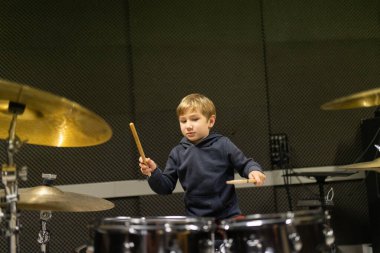 Ses geçirmez stüdyoda bateri çalan genç bir çocuk.