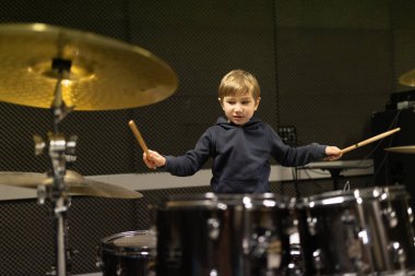 Elinde bagetlerle ses geçirmez bir müzik stüdyosunda davul çalıyordu.