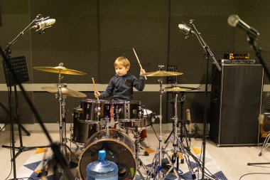 Davul çalan genç bir çocuk, modern ses geçirmez bir stüdyo ortamında müzik yeteneği geliştiriyor.