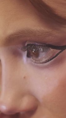 Makyaj yapan genç ve güzel bir kadının dramatik kanatlı göz kalemi çizimi. Kapat.