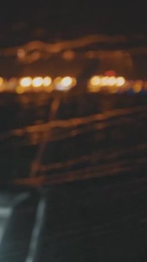 Raindrops smeared on the glass of the porthole as the plane takes off into the sky at night.. Passenger POV