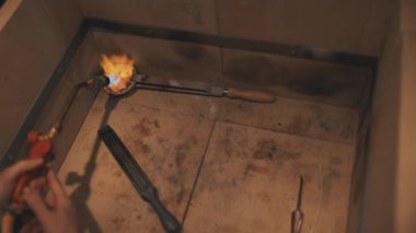 Yetenekli kuyumcu, mücevher üretimi için bir potada altın eritmek için gaz feneri kullanıyor.