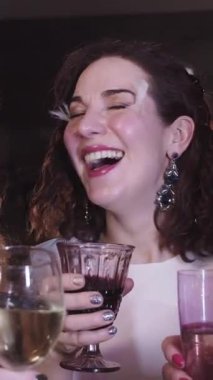 Süslü kıyafetler içinde güzel bir yetişkin kadın parti veriyor. Köpüklü şarap içiyor, iletişim kuruyor ve gülüyor. Orta çekim