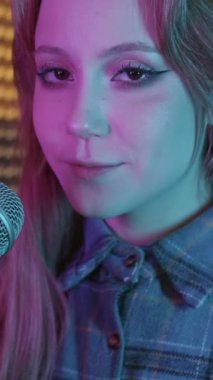 Kanatlı göz kalemi kullanan güzel bir kadın kameraya yaklaştı ve mikrofonda şarkı söylemeye başladı. Portre