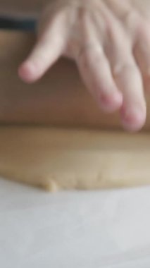 Masanın üzerinde merdaneyle hamuru yuvarlayan kadın elleri. Orta çekim