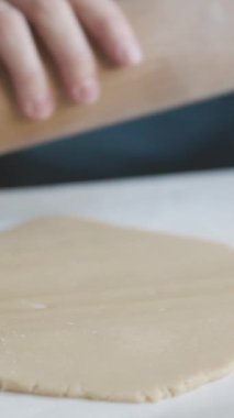 Masanın üzerinde merdaneyle hamuru yuvarlayan kadın elleri. Orta çekim