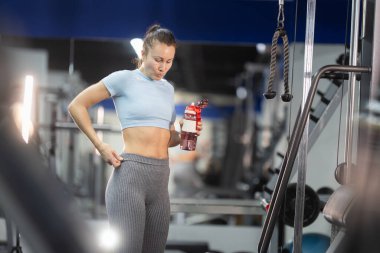 Bel bandı ayarlayan, spor salonunda egzersiz yaptıktan sonra vücudundaki değişiklikleri gözlemleyen bir kadın.