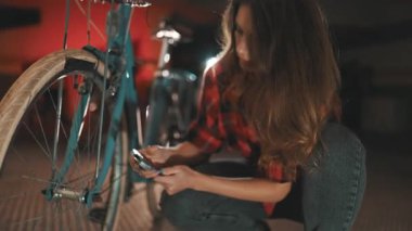 Bisiklet bakımı yapan bağımsız genç bir kadın. Garajdaki İngiliz anahtarıyla direksiyondaki cıvataları sıkıyor.