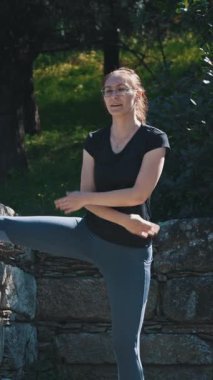 Atletik kadın parkta esneme hareketleri yapıyor. Orta çekim