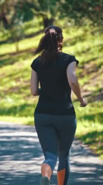 Yetişkin bir kadın parkta koşuyor. Orta çekim