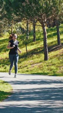 Gözlüklü yetişkin bir kadın parkta koşuyor. Orta çekim