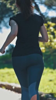 Yeşil parkta koşan sportif bir kadın. Orta çekim