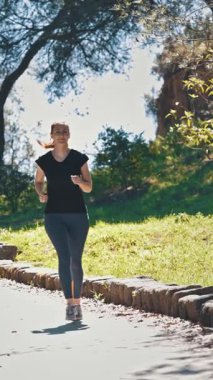 Yeşil parkta koşan sportif bir kadın. Ön manzara. Orta çekim