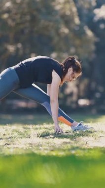 Yetişkin sporcu kadın vücudunu doğada ısıtıyor. Orta çekim