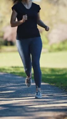 Parkta koşan gerçek bir kadın, bacakları kapalı. Orta çekim