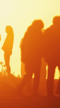 Gün batımında siluet halindeki insanlar - insanlar bisiklet ve scooterlara biniyor. Orta çekim