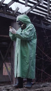 Koruyucu giysili ve gaz maskeli bir adam telefon kullanıyor. Orta çekim