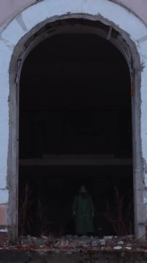 Kıyamet sonrası konsepti. Gaz maskeli ve koruyucu kıyafetli bir adam terk edilmiş binadan çıkıyor. Orta çekim