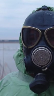 Kıyamet sonrası konsept - gaz maskeli bir adam bulutlu bir manzaranın arka planında koruyucu elbise giyiyor. Portre