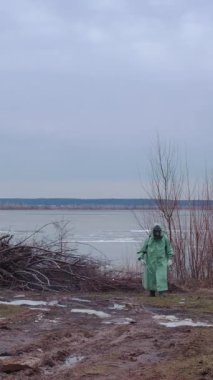 Kıyameti andıran bir kavram. Gaz maskeli bir adam bulutlu bir yerde koruyucu kıyafet giyiyor. Orta çekim
