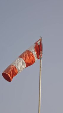 Bulutlu gökyüzünün arka planında çizgili rüzgarlık. Orta çekim