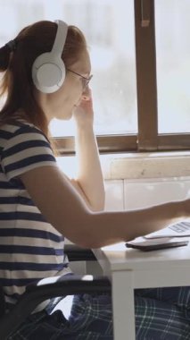 Genç bir kadın kahvaltı yapıyor, kahve içiyor ve dizüstü bilgisayara bakıyor. Orta çekim