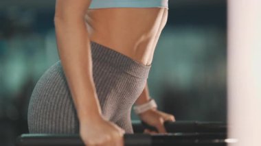 Spor salonunda üst vücut kuvveti eğitimi için triseps dalış egzersizi yapan kaslı kadın.