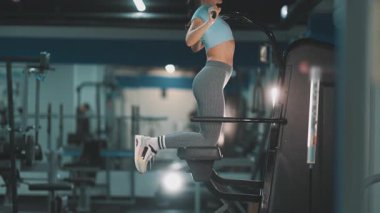 Atletik kadın modern bir spor salonunda sırt ve kol kasları için güç antrenmanı yapıyor.