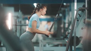 Atletik kadın, modern bir spor salonunda iple bastırma egzersizi yapıyor.